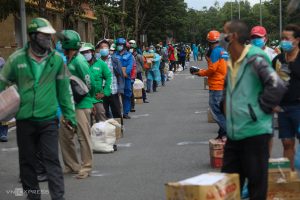 Xe ôm công nghệ giao hàng xếp thành 5 hàng chờ đến lượt đưa hàng. Lực lượng chức năng dùng sơn đánh dấu dưới đường để họ giãn cách 1,5 m.
